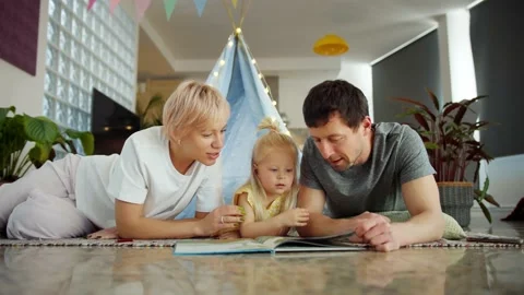 Affectionate parents spending time with little cute daughter reeding book Stock Footage 131550008