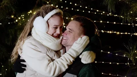 Affectionate partners cuddling closely, softly laughing beneath twinkling string Stockbeeldmateriaal 321434819