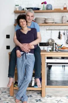 An affectionate smiling mixed couple in their kitchen Stock Photos
