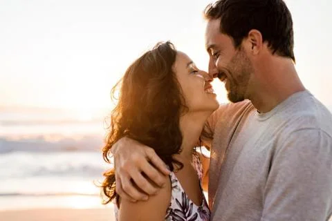 Affectionate young couple hugging on a beach at sunset Stock Photos
