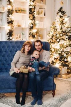 Affectionated couple on blue couch under snowflakes falling down. Photos