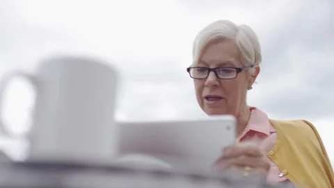 Affluent senior couple at a breakfast table outdoors using digital tablets Video stock 91505768