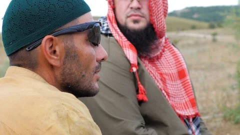 Afghans. one of them smokes a cigarette, the other in keffiyeh wary looks around Stock Footage 129692014