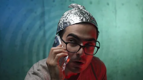 Afraid and Scared Man Wearing a Tin Foil Hat Talking on the Phone Vídeos de archivo 136131507