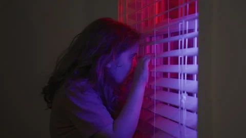 Afraid child hides alone in dark room. Afraid kid watches police flashing lights Video stock 328958192