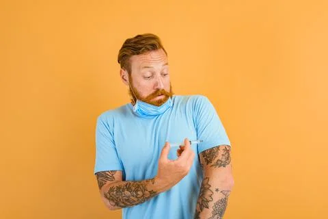 Afraid man with beard, tattoo and mask for covid-19 is ready for the virus Stock Photos
