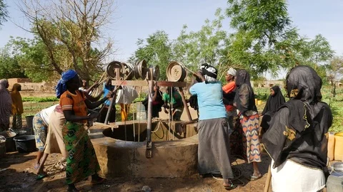 Africa niger women pull water from a well in a vegetable garden. Stock Footage