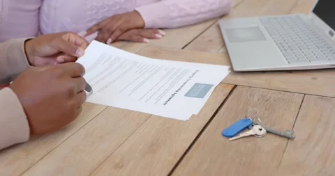 African advisor and client reviewing printed paper at table, advisor pointing Stock Footage 339495764