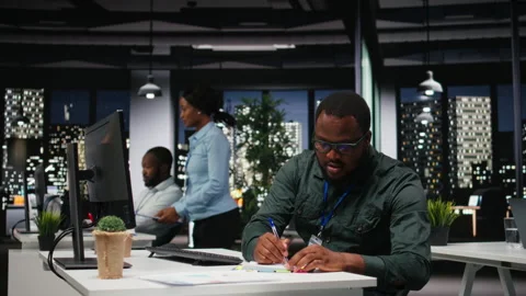 African american advisor extracting data by hand on a notebook late at night Stock Footage 318497055