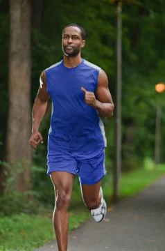 African american athlete running on a wooded path Stock Photos
