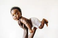 An African-American Baby Being Held Up In The Air By Her Parent Against A Whi Stock Photos