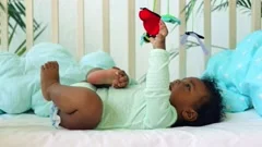 Black baby boy lying on his backside with his legs up in the air