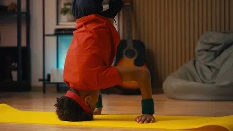 African American boy doing headstand during breakdance, active hobby at home Stock Footage 318545463