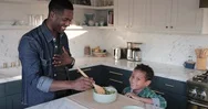 African American Boy Helping Father Prepare Healthy Meal In Kitchen Stock Footage
