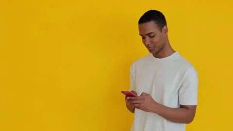 African american boy using mobile phone over yellow background Stock Footage 271324066