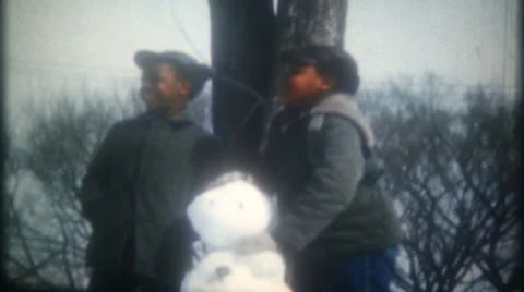 African American boys build snowmen on winter day 1950s vintage film home movie Stock Footage