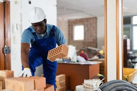 African american builder stacking bricks in building under renovation Foto stock
