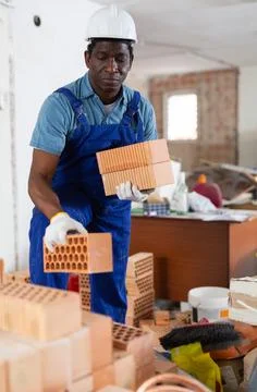 African american builder stacking bricks in building under renovation Foto stock