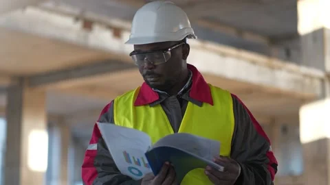 African american builder stands at construction site, holds in hands work papers Stock Footage 195239660