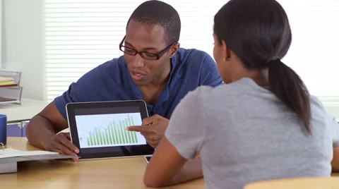 African American business man sharing graphs with coworker on tablet Stock Footage