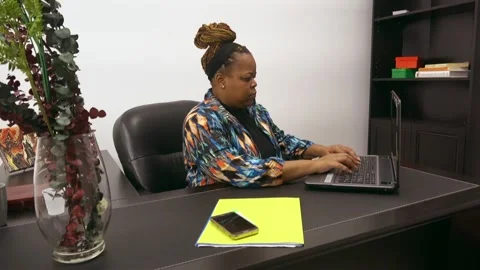 African American business owner typing on computer and checking phone for Stock Footage