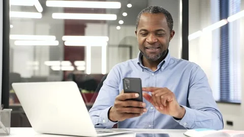 African american businessman is using browsing mobile phone while sitting  Stock Footage 327362579