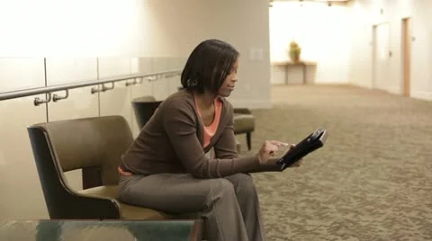 African American businesswoman sitting in office hallway using digital tablet Stock Footage