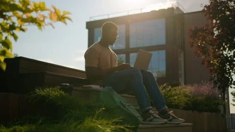 African American busy student guy studying outdoors in city with laptop Stock Footage 252829440