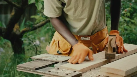African American carpenter in goggles processes wooden board Video stock 198382641