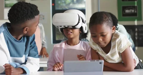 African American child after tech lesson putting on white VR headset at desk 스톡 동영상 344644858