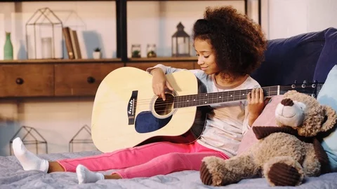 African american child playing acoustic guitar in bed Stock Footage