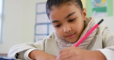 African American child starting classwork at school, writing with pink pencil Stock Footage 340655718