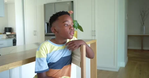 African American child on stool at kitchen island thinking, turning toward Stock Footage 335683235