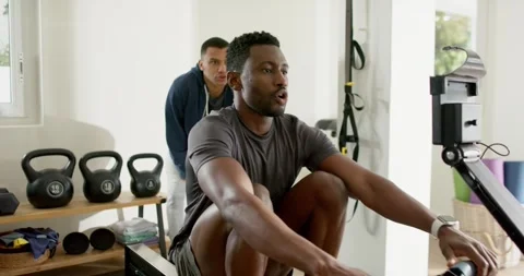 African American client initiating stroke on rowing machine at home gym with Stock-Footage 345071105