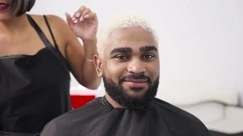 African american client looking at camera and hairdresser working at hair dy Stock Footage 285502071