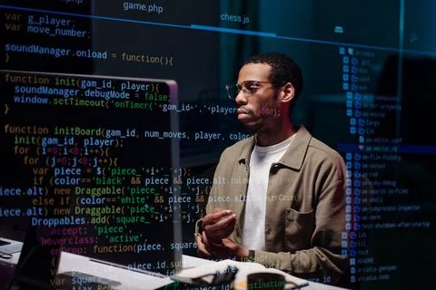 African American Coder Analyzing Complex Code on Screen Foto stock
