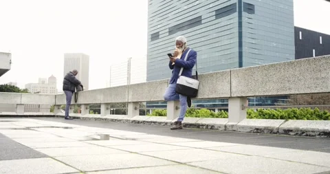 African American colleagues opening backpack to grab pastry while scrolling Stock Footage 339651053