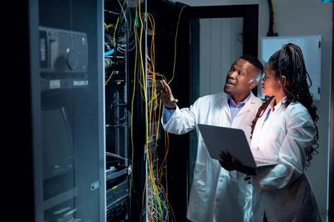 African american computer technicians using laptop working in server room Stock-Fotos