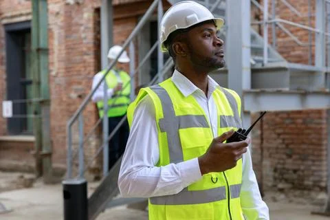 African american controller in protective hardhat using walkie talkie for Stock Photos