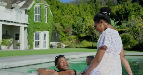 African American couple chatting poolside, man resting with shades, woman on Stock Footage 344254604