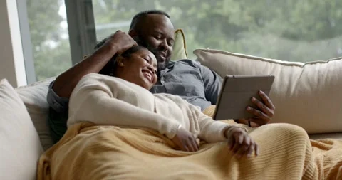 African-American couple on couch, camera pulling back, man cradling her head Stock Footage 338337302
