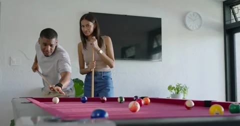 African American couple playing by pool table at home, man pointing and teaching Видео 337730288