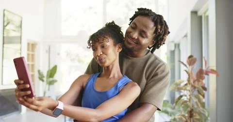 African American couple posing for selfie, woman in blue top holding pink phone 库存影片 339651753