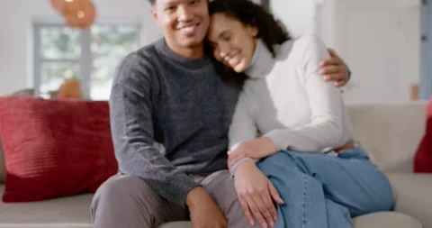 African American couple posing while lens pulling focus from mugs to couch, Stock Footage 345090157