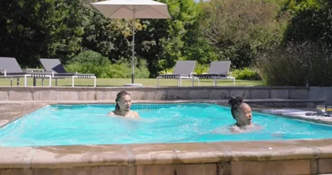African American couple preparing on pool coping, jumping, splashing, playing, Stock Footage 341469393