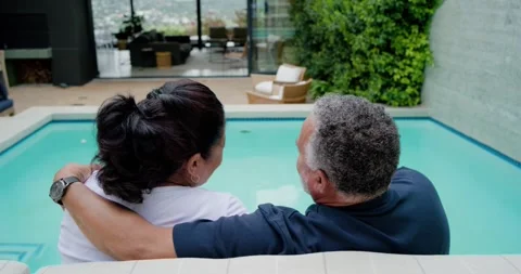 African American couple sitting poolside bench man placing arm around her Stock Footage 336484290