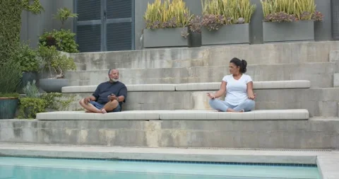 African American couple sitting poolside, woman opening eyes, man lifting phone, Stock Footage 336784819