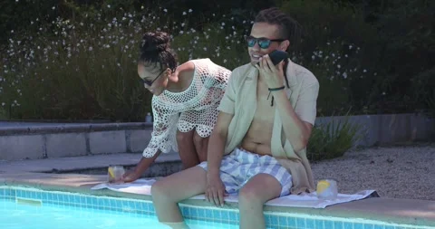 African American couple sitting poolside, woman bringing lemon drink, man ending Stock Footage 336898148