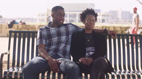 African American couple sitting together on a bench on the city Stock Footage