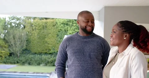 African American couple smiling, posing on patio poolside as woman entering from Stock Footage 342066281